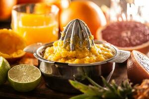 Squeezed orange pulp in a juicer with cfreshly cut citruses and a glass of juice photo