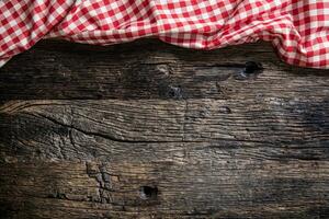 Red checkered kitchen tablecloth on rustic wooden table photo