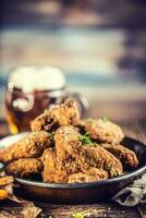 Fried chicken wings fries and draft beer on table. photo