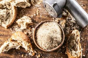 A wooden bowl full of breadcrumbs and old dry bread around photo