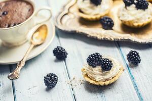 mini tartaletas con moras azotado crema y café. foto