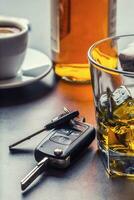 Car keys and glass of alcohol on table. photo
