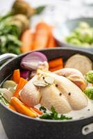 Chicken ready to cook broth with fresh root vegetables and spices photo