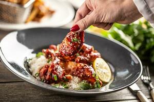 Spicy glazed chicken thighs and wings served with rice and coriander leaves photo