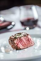 Beef tenderloin steak on white plate and red wine in pub or restaurant photo