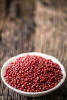 Red peppercorn in bowl on oak table photo