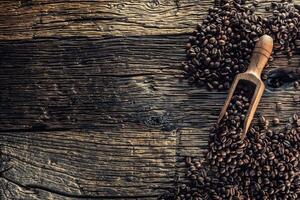 Wooden scoop full of coffee beans on old oak table photo