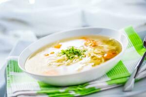 Lunch setting table with chicken or beef soup with noodles carrot and herbs photo