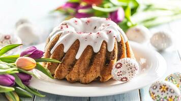 Festive easter marble cake with icing sugar hand-decorated eggs and spring tulips photo