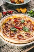 Pizza salami diavola with red onion basil and chili pepper photo