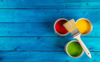 Paint cans color palette, cans opened with brushes on blue table photo