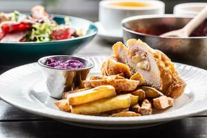 Chicken cordon bleu with ham and cheese inside served with fried potato wedges and red cabbage salad photo