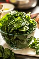 Glass bowl full of homegrown healthy green spinach. photo