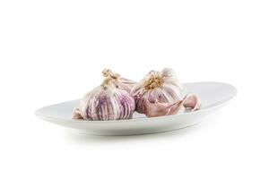 Fresh garlic bulbs in plate isolated on white background photo