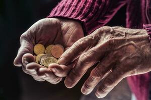 Pensioner man holding in hands euro coins. Theme of low pensions. photo