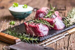 Raw beef meat. Raw beef tenderloin steak on a cutting board with rosemary pepper salt in other positions. photo