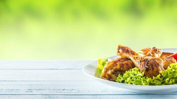 Roasted chicken legs with lettuce salad and tomatoes photo