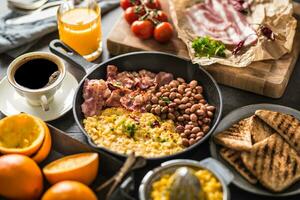 lleno mesa de Inglés desayuno. revuelto huevos A la parrilla tocino frijoles brindis un pan naranja jugo y café foto