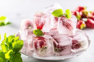 Frozen strawberries in ice cubes on a plate. photo