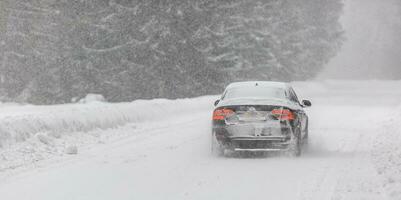 Liptov, Slovakia - JANUARY 30, 2022. Car covered in snow driving in snowstorm on a cold winter day photo