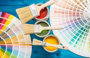 Paint cans color palette, cans opened with brushes on blue table photo