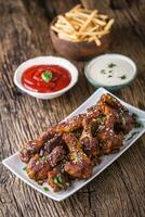 Chicken wings. Fried chicken wings in white bowl garlic dressing ketchup and potato fries. photo