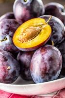 Plums. Fresh juicy plums in a bowl on a wooden or concrete board photo