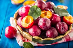 Plums. Fresh juicy plums in a bowl on a wooden or concrete board photo