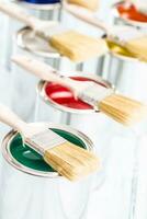 Close-up brushes lying on multicolored paint cans. photo