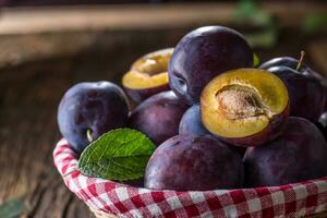 Plums. Fresh juicy plums in a bowl on a wooden or concrete board photo