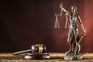 Lady Justicia holding sword and scale bronze figurine with judge hammer on wooden table photo