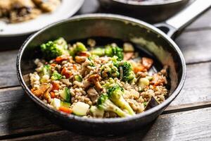 Healthy vegan meal of groats served with broccoli, carrots, and mushrooms in a pan photo