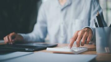 Businessman using calculator to calculate numbers ,profit and loss statement review of company performance ,Cost analysis and calculation of financial documents ,business account checking photo