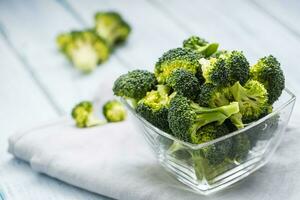 Fresh broccoli in bowl on kitchen table photo