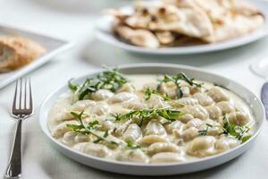 Creamy gnocchi with four types of cheese and ruccola on top photo