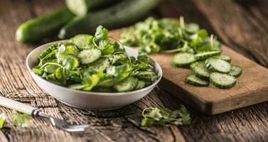 Sliced cucumber on a plate with parsley herb on rustic oak wood. photo