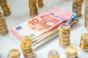 Euro banknotes and coins togetger on white table - close-up photo