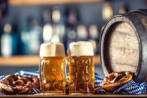 Oktoberfest two large beer with pretzel wooden barrel and blue tablecloth photo