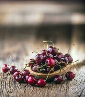 Cherries. Fresh sweet cherries. Delicious cherries with water drops in retro bowl on old oak table. photo