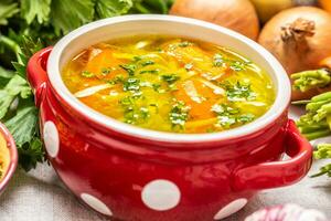 pollo sopa caldo en un Clásico cuenco con hecho en casa tallarines Zanahoria cebolla apio hierbas ajo y Fresco vegetales foto