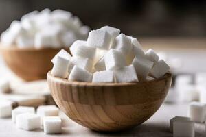 White sugar cubes in a wooden bowl on the table photo