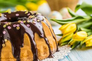 Delicious holiday slovak and czech cake babovka with chocolate glaze. Easter decorations - spring tulips and eggs photo