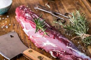 Raw beef meat. Raw beef tenderloin steak on a cutting board with rosemary pepper salt in other positions. photo