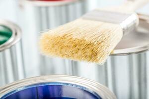 Close-up brush lying on multicolored paint cans. photo