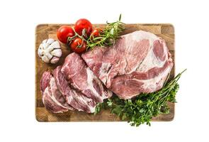 Pork neck raw meat with garlic parsley herbs tomatoes and rosemary on butcher board isolated on white background photo