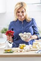 mujer participación cuenco de Fresco ajo y chiles haciendo conservas en el cocina foto