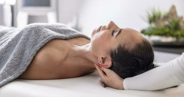 Masseuse does detailed massage of a female client by rubbing the end of her neck and the final muscles close to her head photo