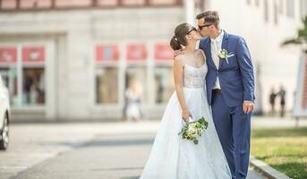 Beautiful couple kissing each other in the middle of the town. They  are just married and are having a photo taken to the album