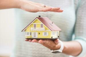 Hands of young woman holding model house photo