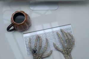 Skeleton hands on a computer keyboard witk spooky light photo